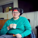 Das Bild zeigt einen der Bewohner mit einer Tasse in der Hand.