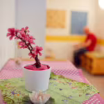 Das Bild zeigt eine pinke Kunstpflanze auf einem Sideboard.