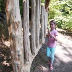Das Bild zeigt ein Kind an einem großen Holz-Xylophon aus Baumstämmen.