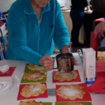 Das Bild zeigt eine Frau, die Waffeln mit Puderzucker bestäubt.