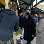 Das Bild zeigt Besucher an einem Verkaufsstand.