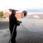 Das Bild zeigt Feuerwehrmann Markus, der den Schlauch auf ein Verkehrshütchen hält.