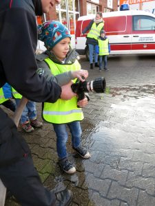 Das Bild zeigt einen Jungen, der einen Feuerwehrschlauch hält.