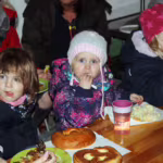 Das Bild zeigt drei Kinder beim Essen.